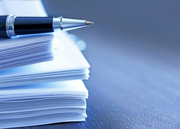 Stock image of papers and pen, resting on a stack of paperwork
