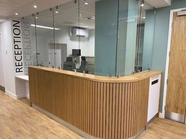 New Reception area with wood curved desk with glass panels to the ceiling