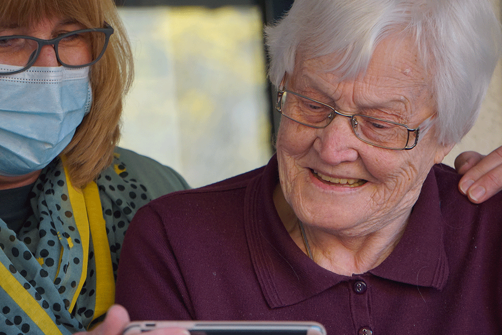 Older lady looking at computer with carer
