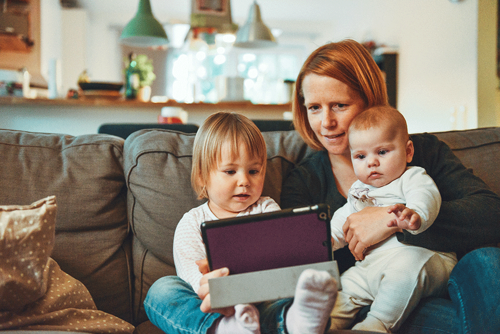 Mother with baby and toddler looking at a laptop