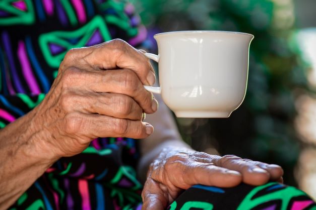 Elderly hand holding tea cup