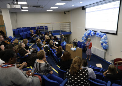 A group of staff members watching a presentation in a lecture hall at the Hospital at Home launch event