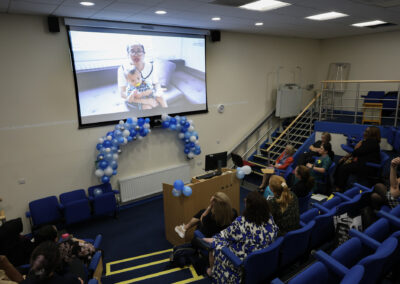 A group of staff members watching a presentation in a lecture hall at the Hospital at Home launch event