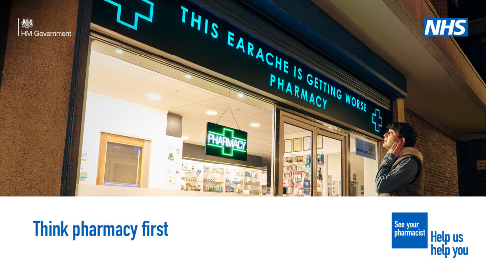 A person is standing outside a pharmacy holding the side of their face in discomfort. The sign above the pharmacy reads 'This earache is getting worse pharmacy'  A lower third box features in the bottom on the image. Text in the box reads: 'Think pharmacy first'