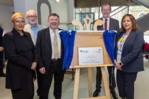 Lena Samuels NLMHP Chair, Jeremy Corbyn MP, Chris Hopson, Alastair Campbell, Jinjer Kandola MBE, NLMHP Chief Executive, standing and smiling near plaque for official opening
