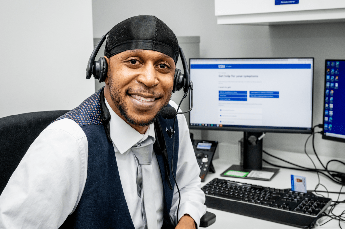 Male receptionist smiling with headset at computer screen