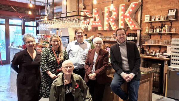 Group of people smiling at Dementia Friendly launch event in the Park Theatre cafe. Back row: Sophia Stevens, Islington Council, Clare Davis, Haringey Council, Paul Allen, NCL ICB, Councillor Janet Burgess MBE, Islington Council, Jez Bond, Park Theatre, Front row: Alan, Park Theatre volunteer.