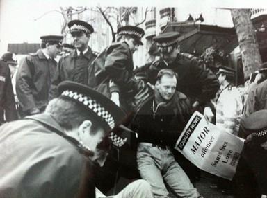 black and white image from the early 1990s of man being arrested by police at sit-in protest