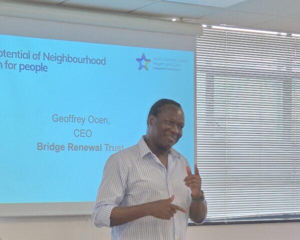 Man in striped shirt smiling and talking. Geoffrey Ocen, CEO, The Bridge Renewal Trust.